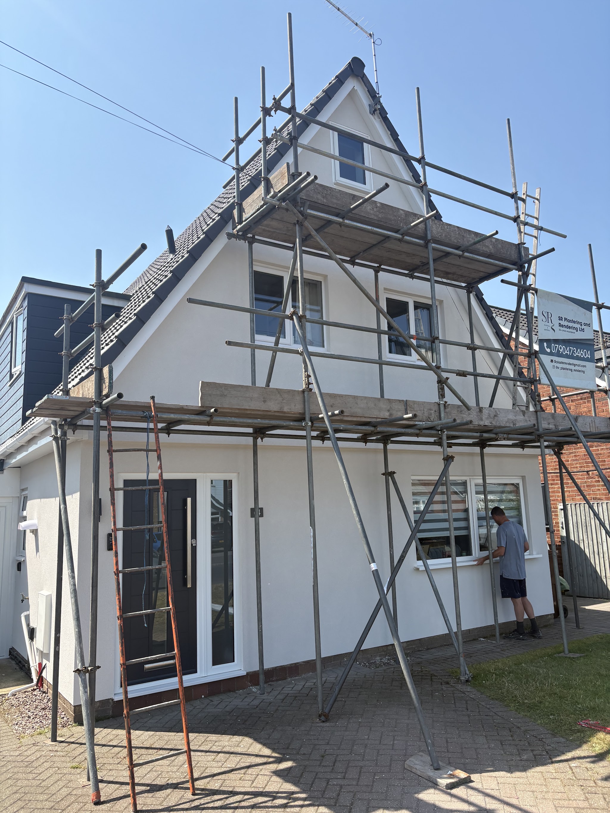 A white rendered gable-fronted house with the scaffold still up