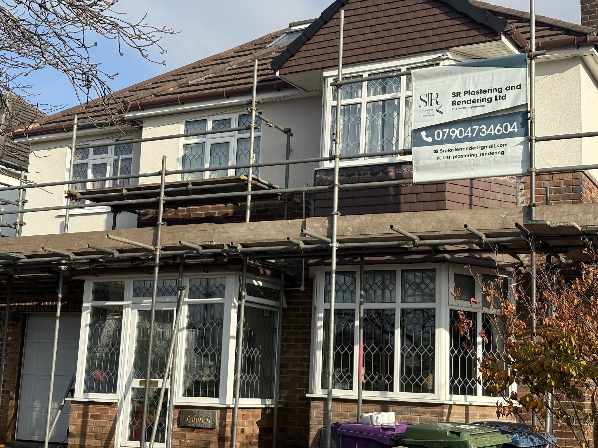 A 1930s semi under scaffold with the SR Plastering and Rendering banner on it
