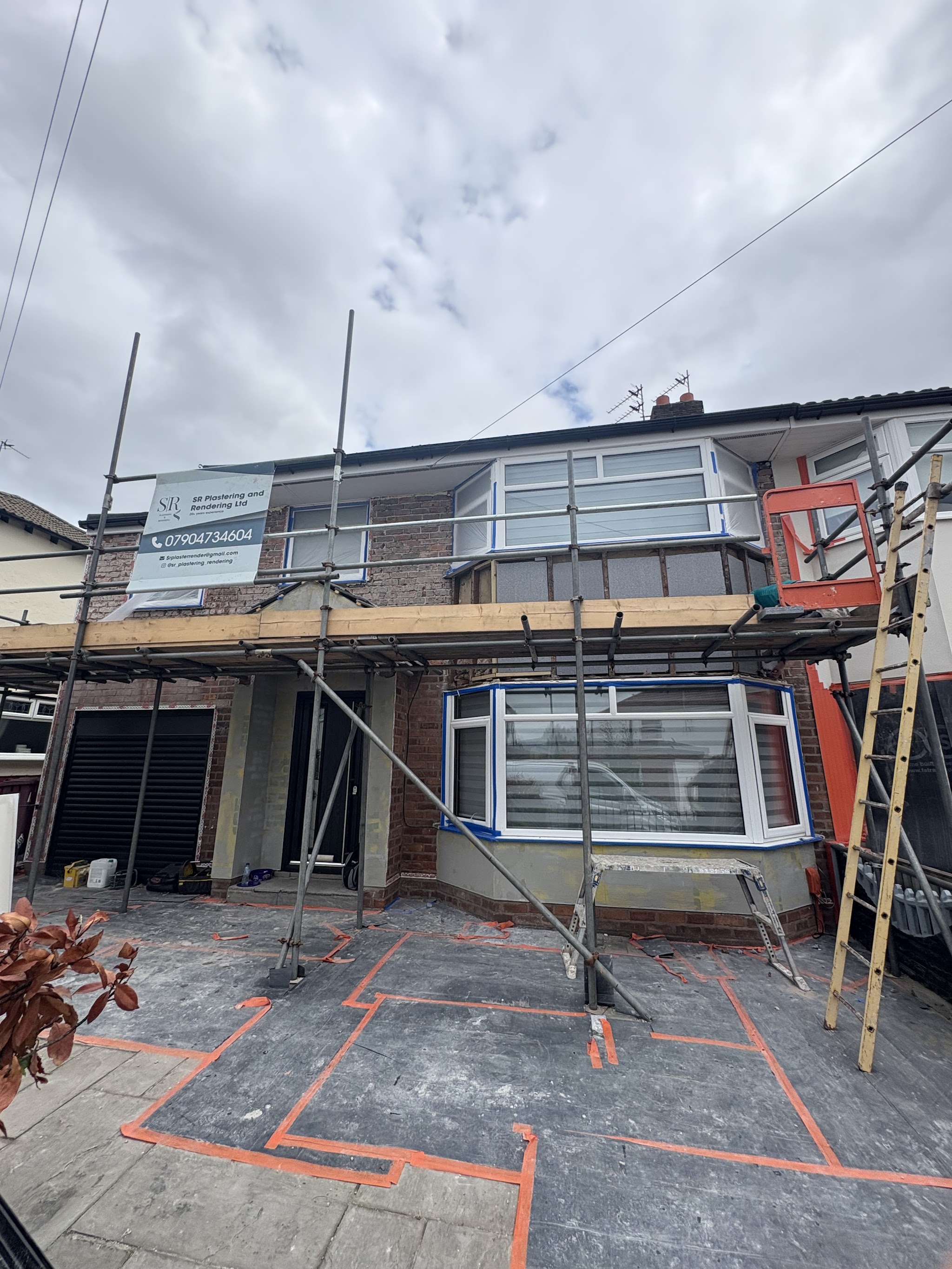 A semi-detached house under scaffold with render in progress